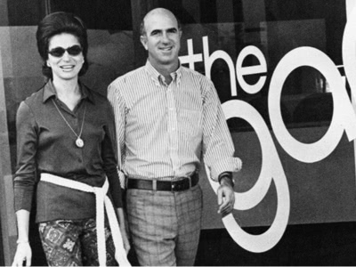 Black and white photo of Doris and Donald Fisher stand smiling in front of their storefront The Gap in 1969.