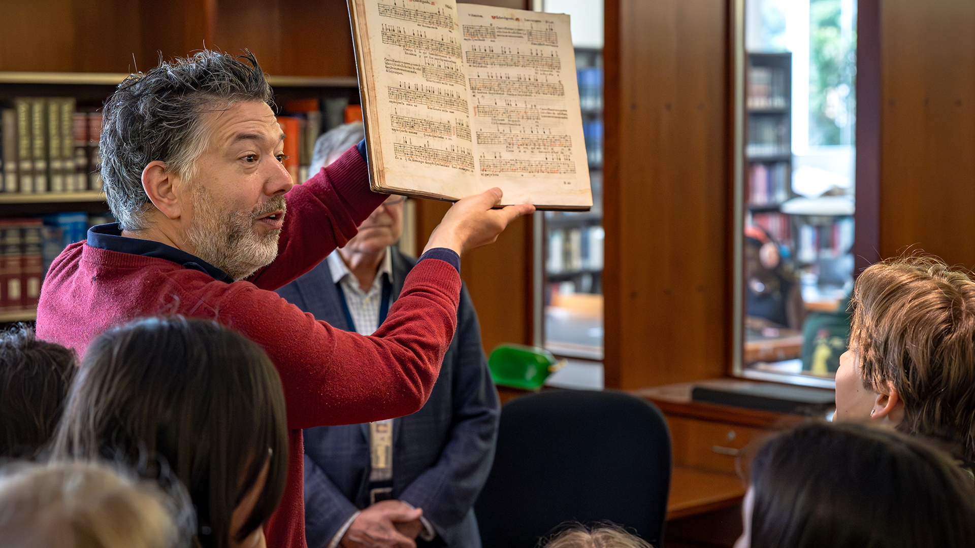 Professor Nicholas Mathew holds up a 500-year-old manuscript to a group of visiting middle school students