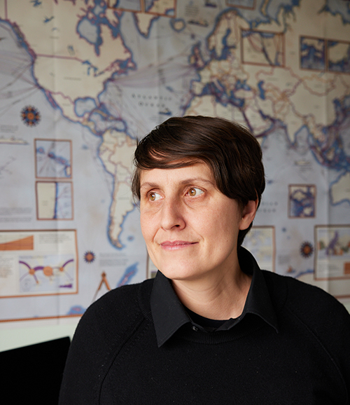 Headshot of Nicole Starosielski with a wall map of the world behind her.