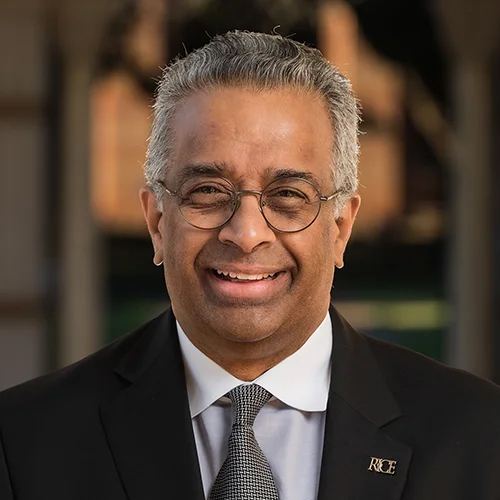 headshot of Ramesh wearing glasses and a suit and tie, smiling at the camera