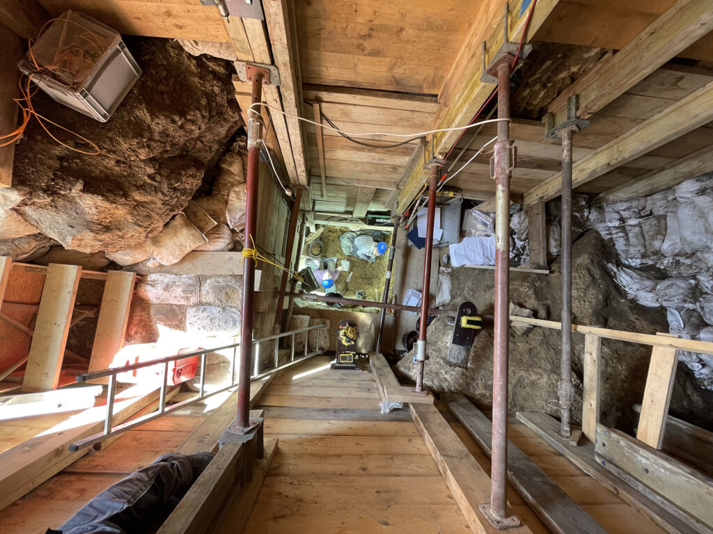 view down into dirt hole with wood and beams supporting walls