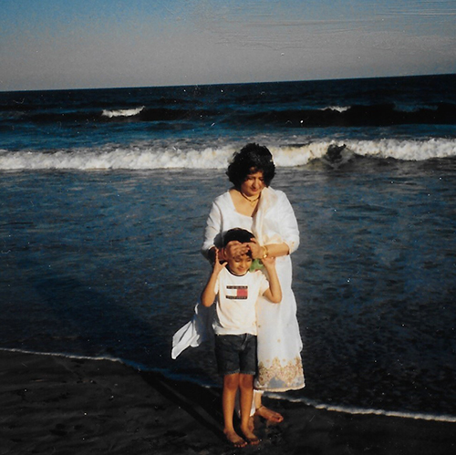 Saagar at age 5 at the beach with his mom, who has her hands on his forehead kind of pulling him close in a playful way