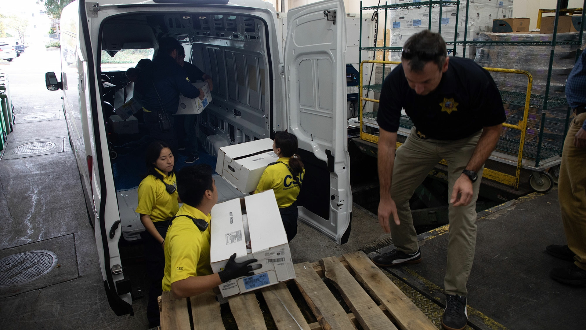 A photo shows volunteers loading boxes of produce into the back of a van.