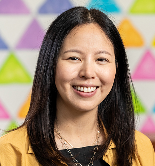 headshot of a person with long dark hair smiling widely