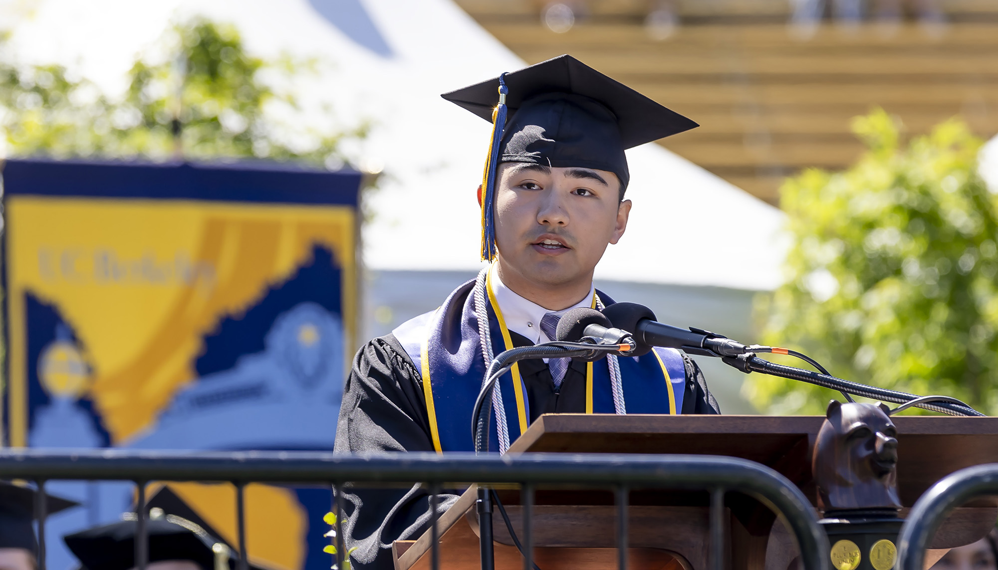 young man in mortarboard and robes at podium