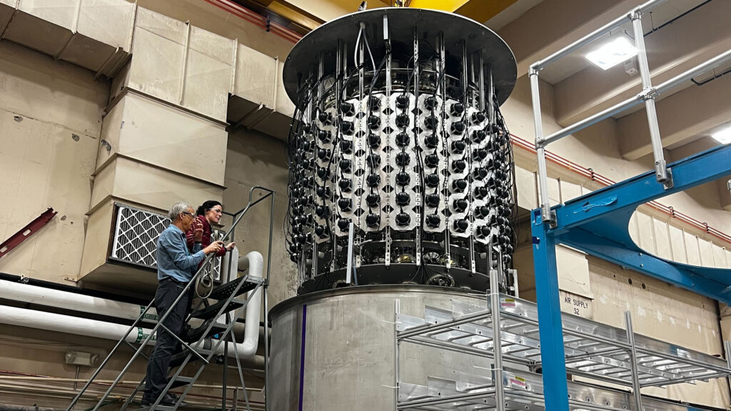 two people inspecting a large cylindrical tank suspended over another tank