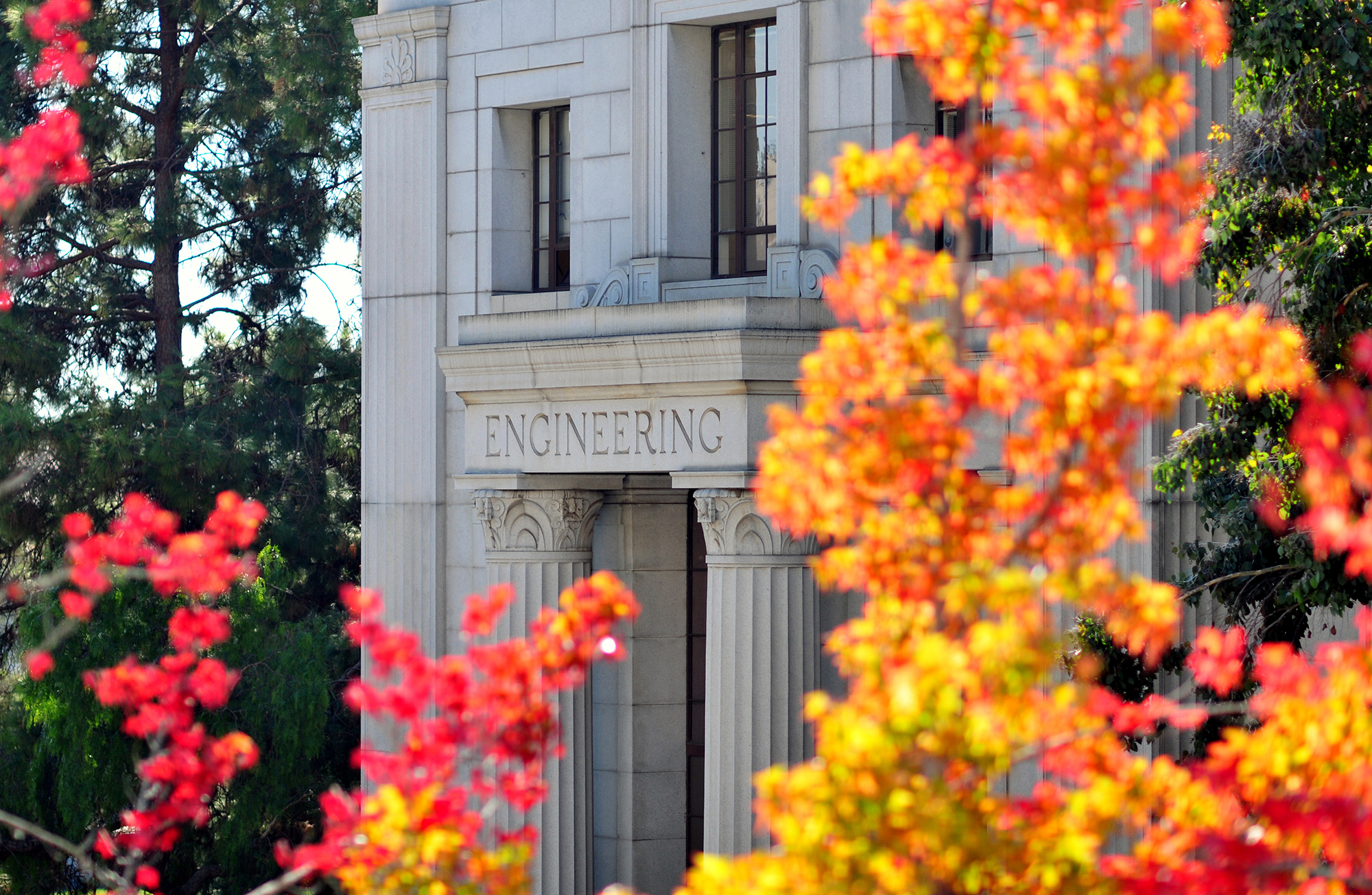 A view of McLaughlin Hall at UC Berkeley flanked by red and orange leaves.
