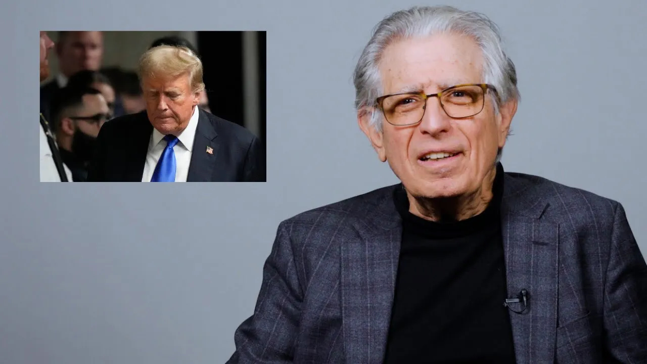 A man in a suit is sitting before a gray background. And inset image shows former President Trump looking downwards.