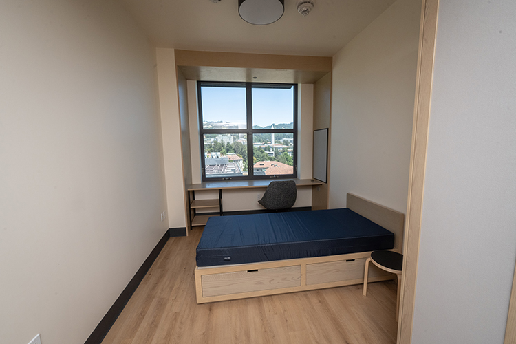 Bedrooms in Anchor House are designed for one student each and offer expansive views of the surrounding area from large screened windows that open. Below each window is a wide, built-in desk, and a built-in armoire and a bed with drawers beneath it offer ample storage. The floors are wood, as is the bed's platform, the desk and the armoire.