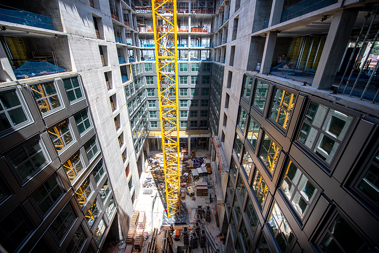 A giant yellow tower crane stands in the middle of the Anchor House construction site in summer 2023.