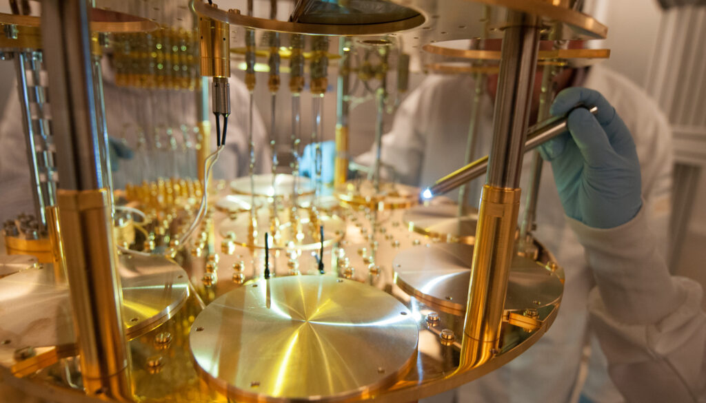 a hand holding a small flashlight to illuminate the gold-plated insides of a quantum computer