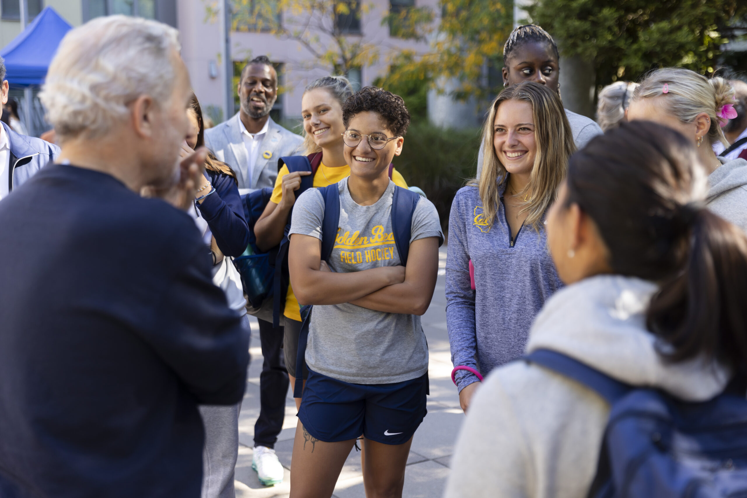 Members of the Cal Women's Field Hockey team meet with Chancellor Lyons on the first move-in day of the fall semester. They are smiling and looking at him while he speaks.