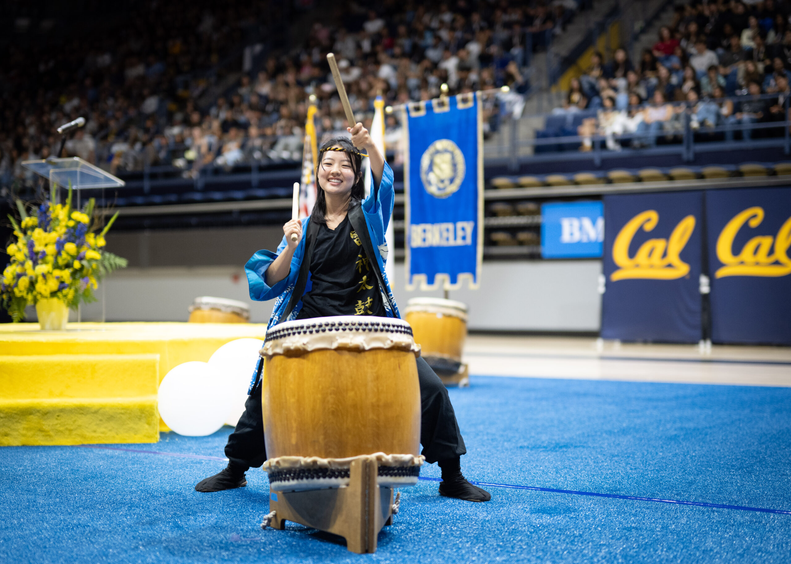 A member of Cal Raijin Taiko, Berkeley’s Japanese drumming ensemble, brandishes their drumsticks in the air.