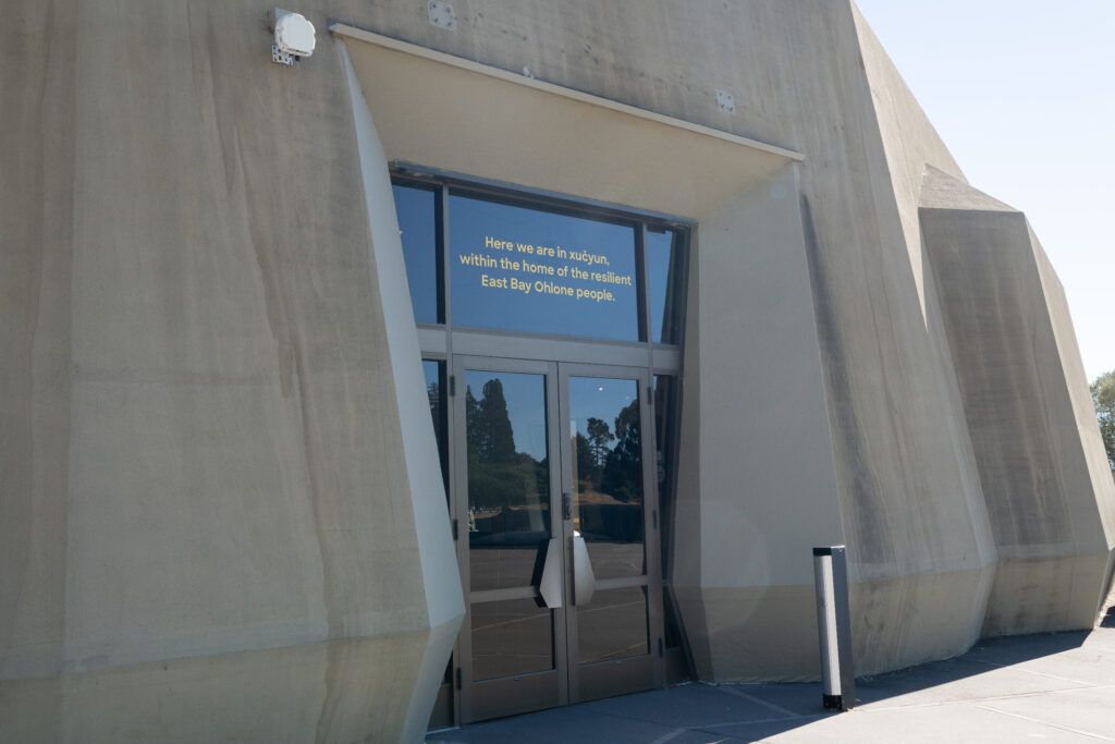 Over the front door to The Lawrence Hall of Science are words painted in gold on the glass that state a land acknowledgement: "Here we are in xučyun, within the home of the resilient East Bay Ohlone people."