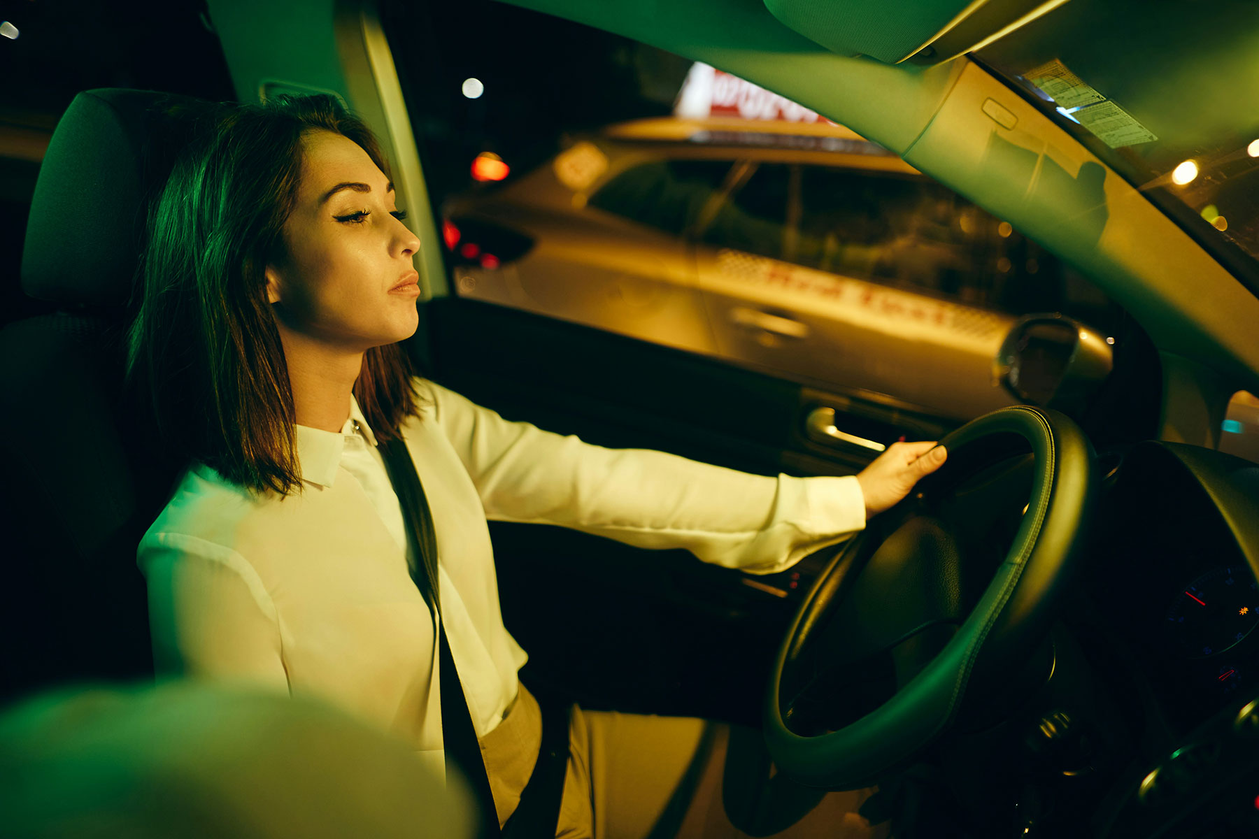 A person is leaning back and closing their eyes while driving a car.