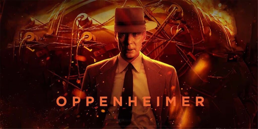 A movie poster for "Oppenheimer" shows the actor who portrayed Robert Oppenheimer looking straight ahead in a suit, tie and hat with shockingly bright shares of red and orange all around and on him and the words Oppenheimer in bright orange across the page.