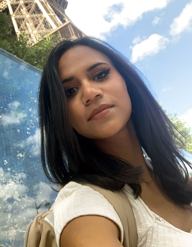 informal portrait of Mira Rubio, with sky and a structure behind her