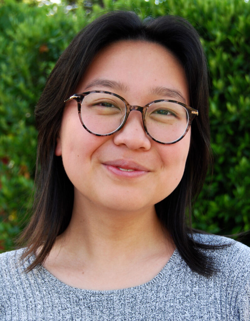 informal portrait of Rena Lu standing against a leafy background