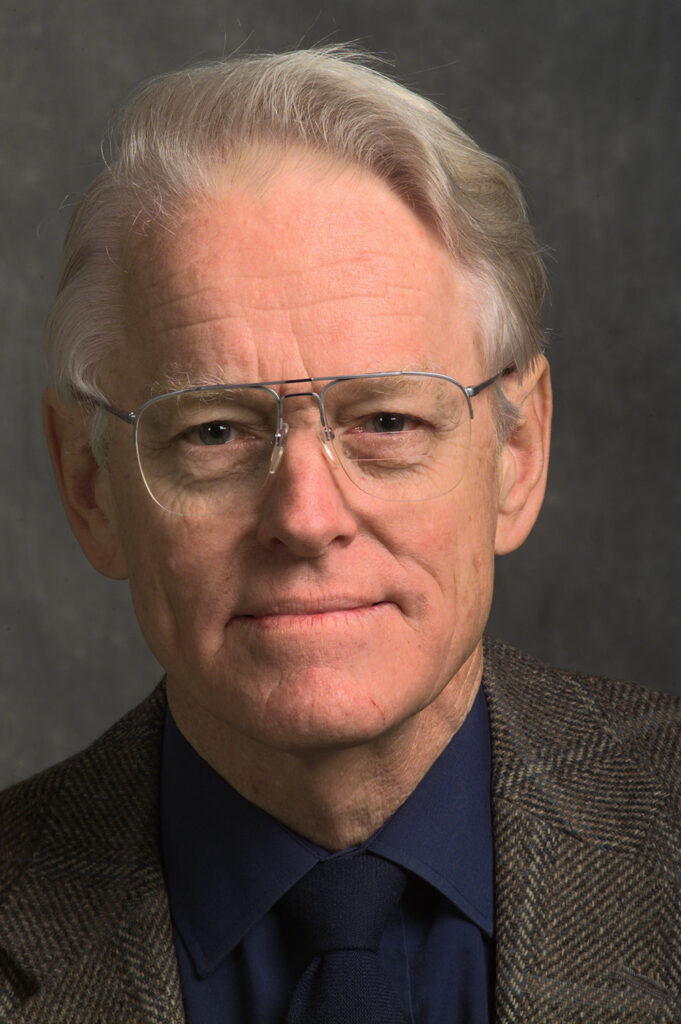 man in glasses, jacket and tie looking at camera