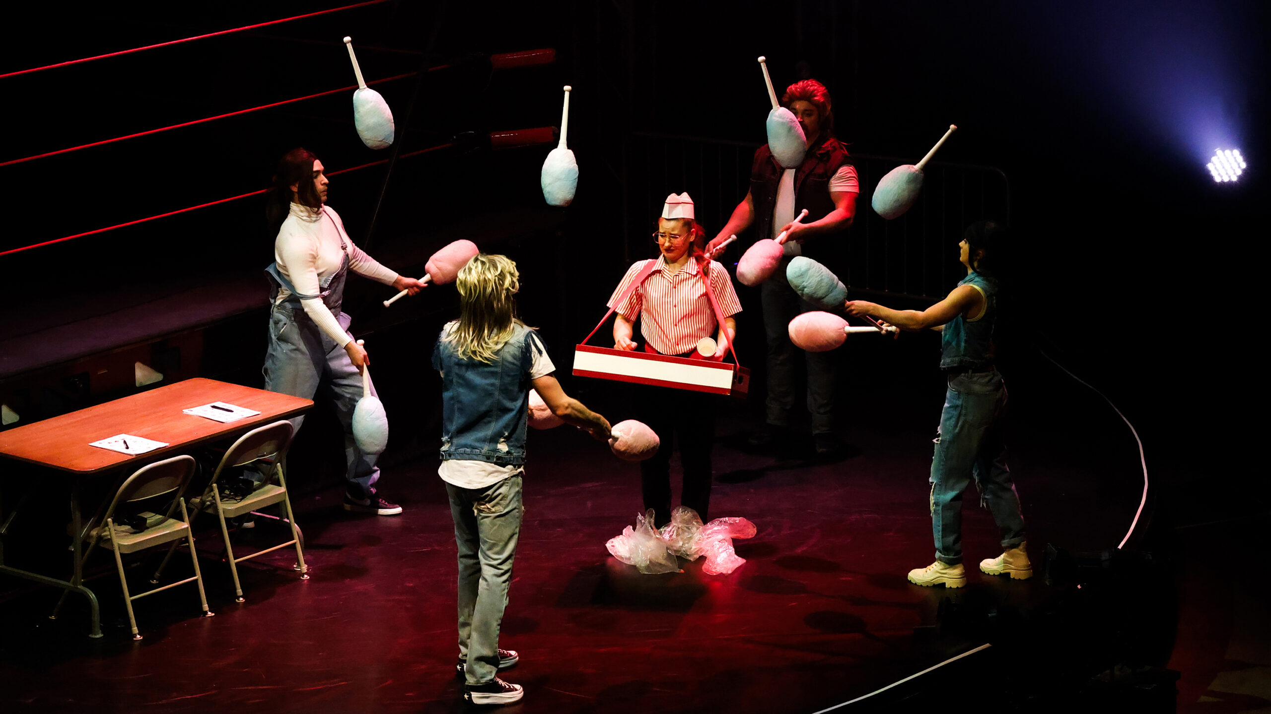 during a circus arts performance, performers juggle cotton candy around a person selling popcorn