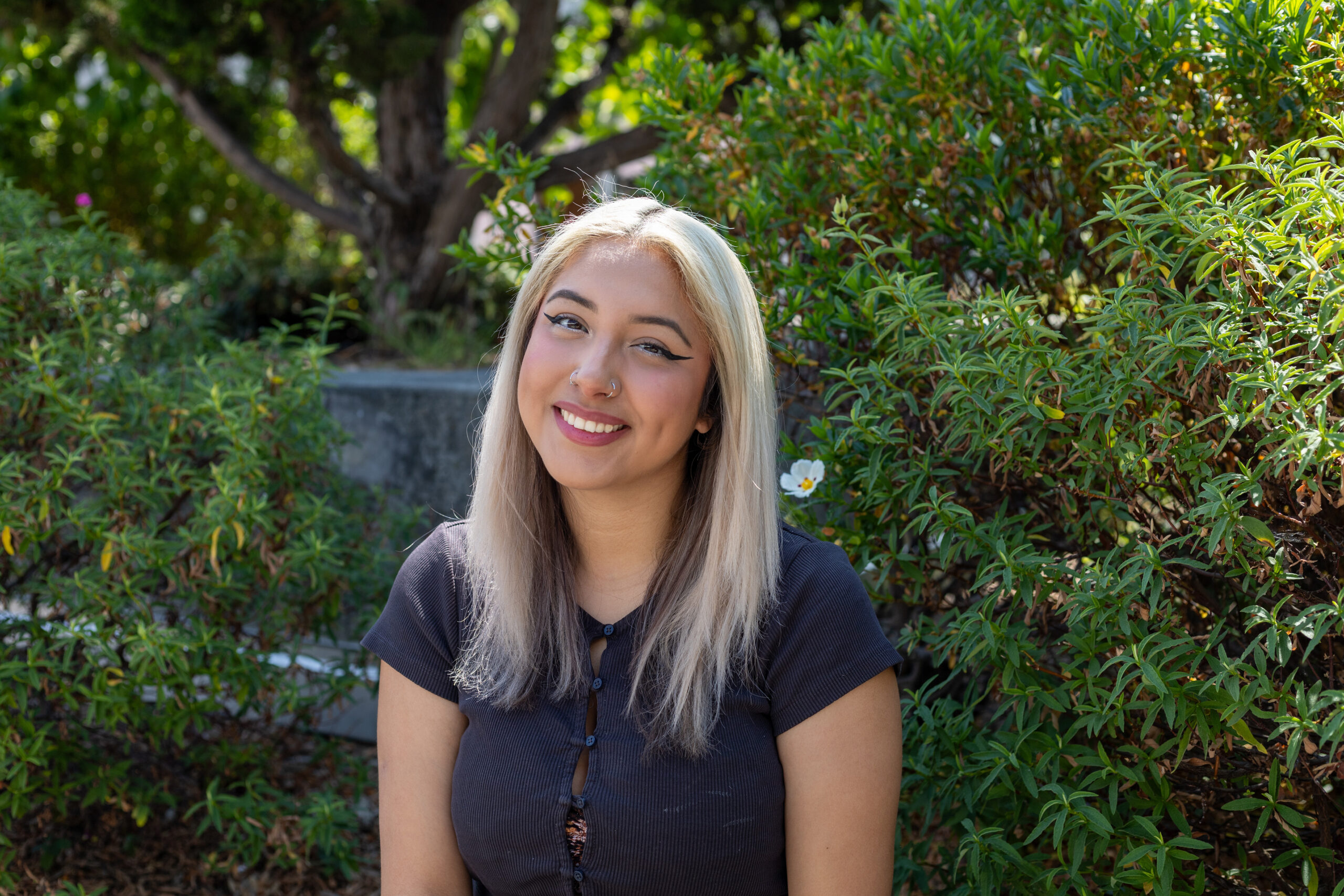 Karla Vega Cervantes, a UC Berkeley Chemical Engineering student, sits before foliage in the background.