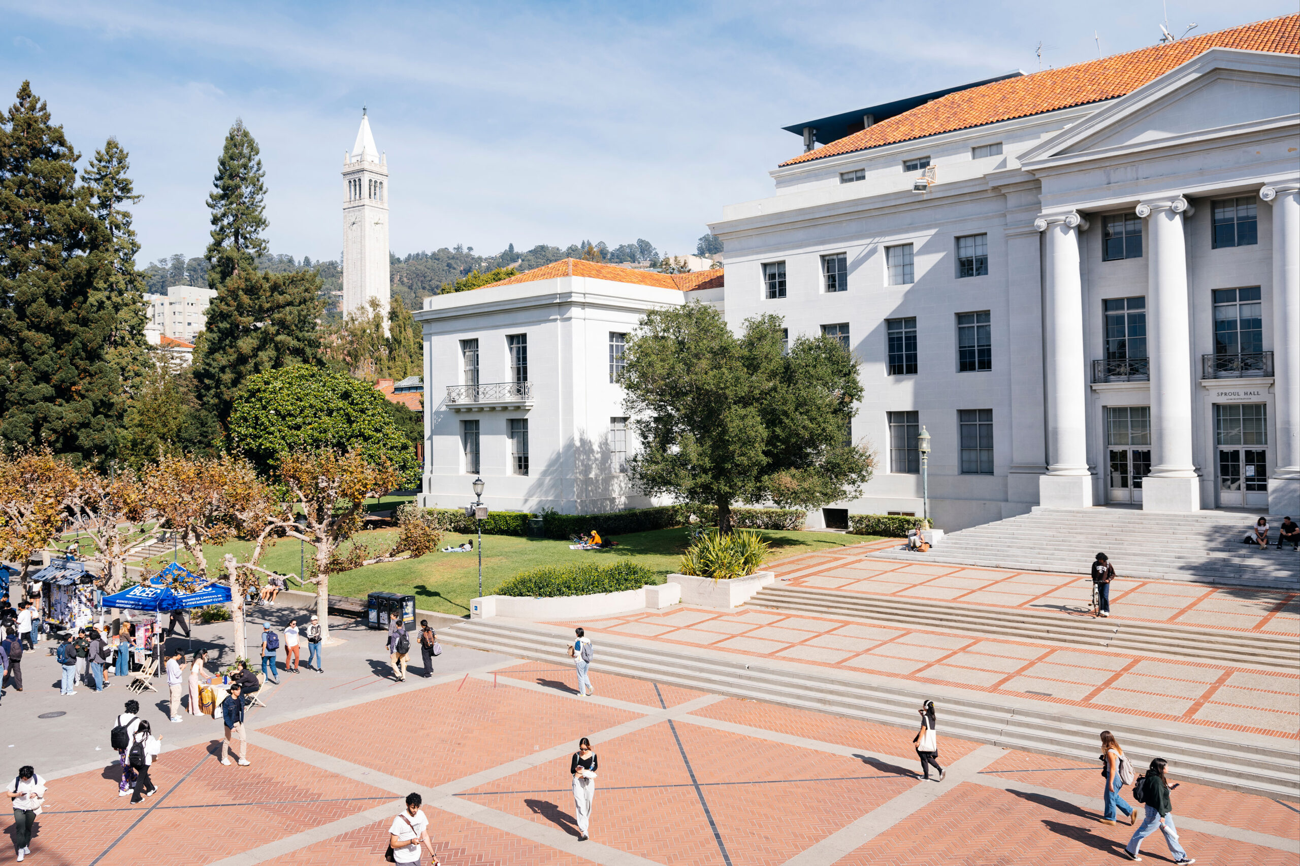 Students walk on the Berkeley campus, with the campanile visible in the background.