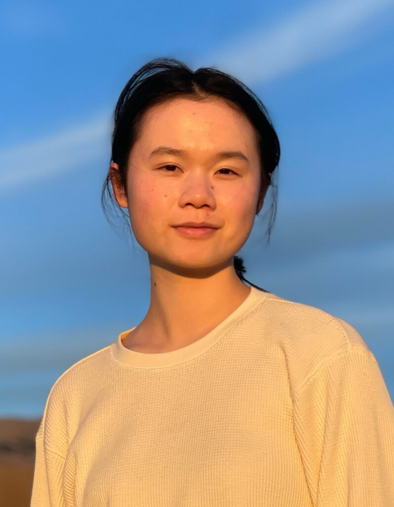 casual portrait of Catherine Tong, in golden late-day light, against a blue-sky streaked with high clouds