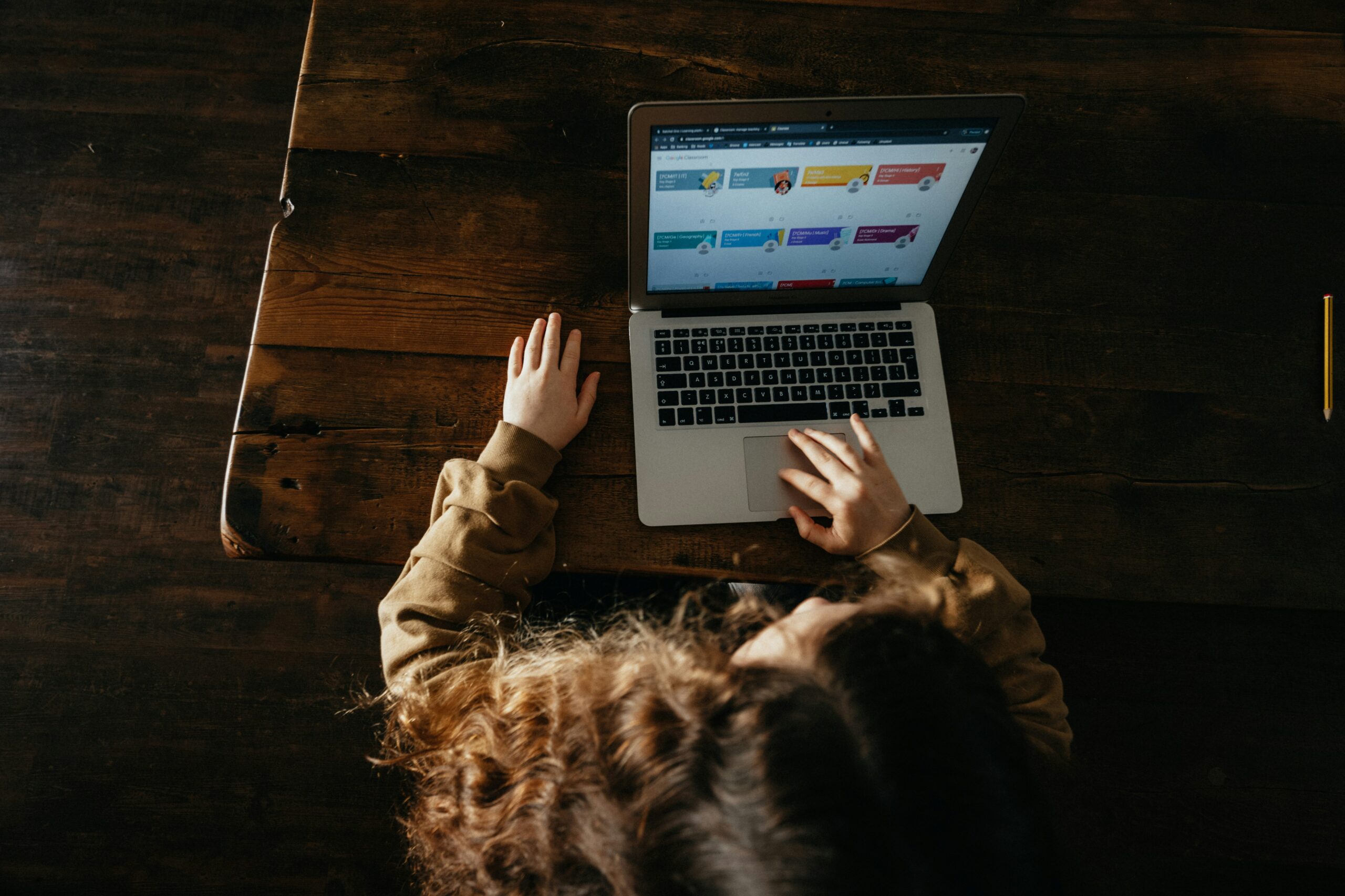 An overhead photo of a child using a laptop, signaling how children spend an increasing amount of time online and may be exposed to increasing amount of concerning content and disinformation