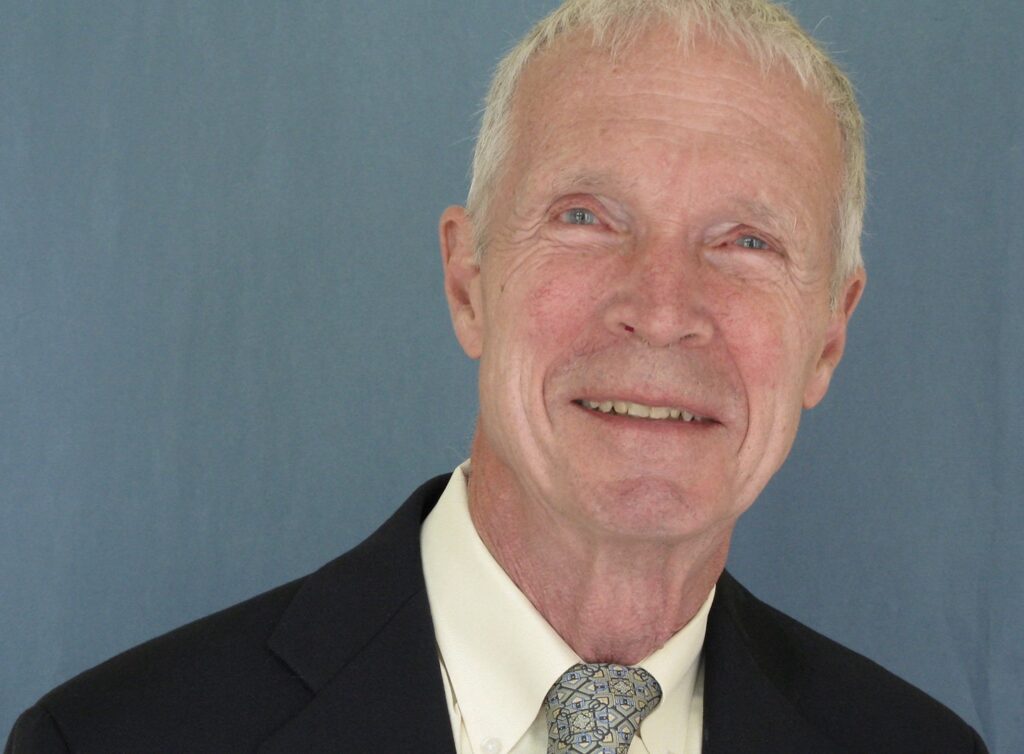 Older man in a suit and tie looks at the camera