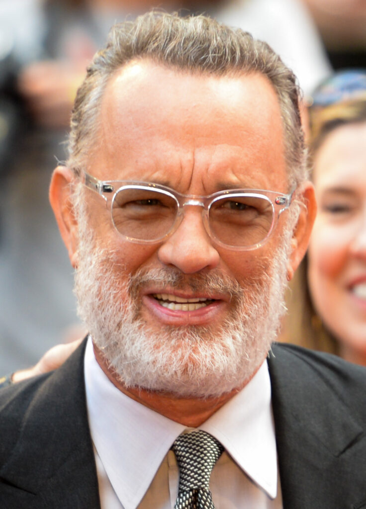 Tom Hanks, wearing glasses and a beard, pictured at a public event.