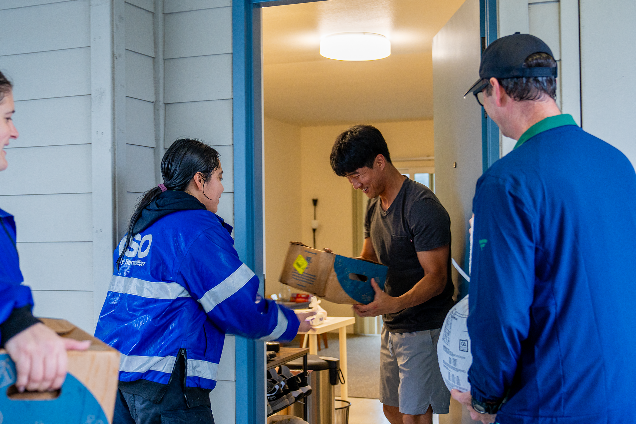 A smiling person looks at a box of produce while a man prepares to hand over a frozen turkey.