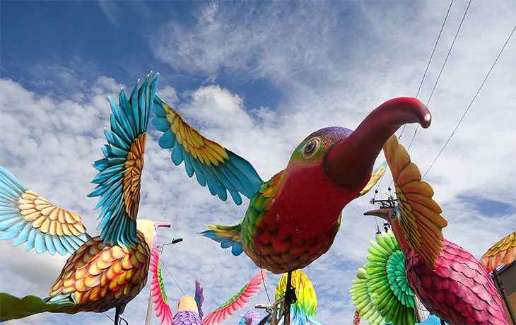 Large and colorful birds made of paper are pictured against a blue sky