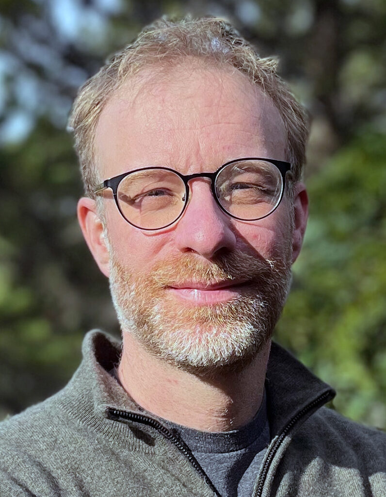 informal headshot of Berkeley political scientists Andrew T. Little against a blurred, leafy backdrop