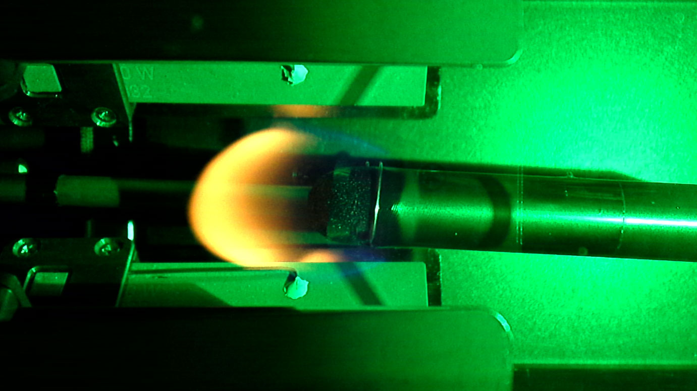 A round shaped yellow flame burns in front of a green background.