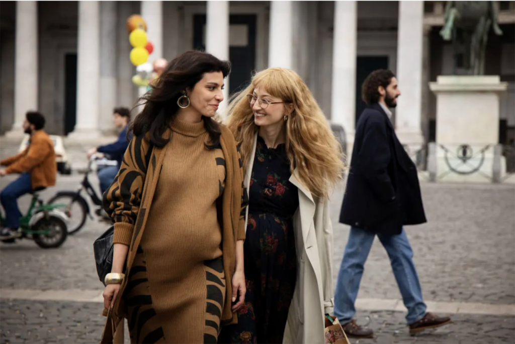 A still taken from the HBO series My Brilliant Friend shows friends Lila and Lenù walking across a street and both of them are pregnant.