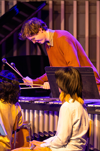 A student plays a percussion instrument on stage at Wu Performance Hall on campus.