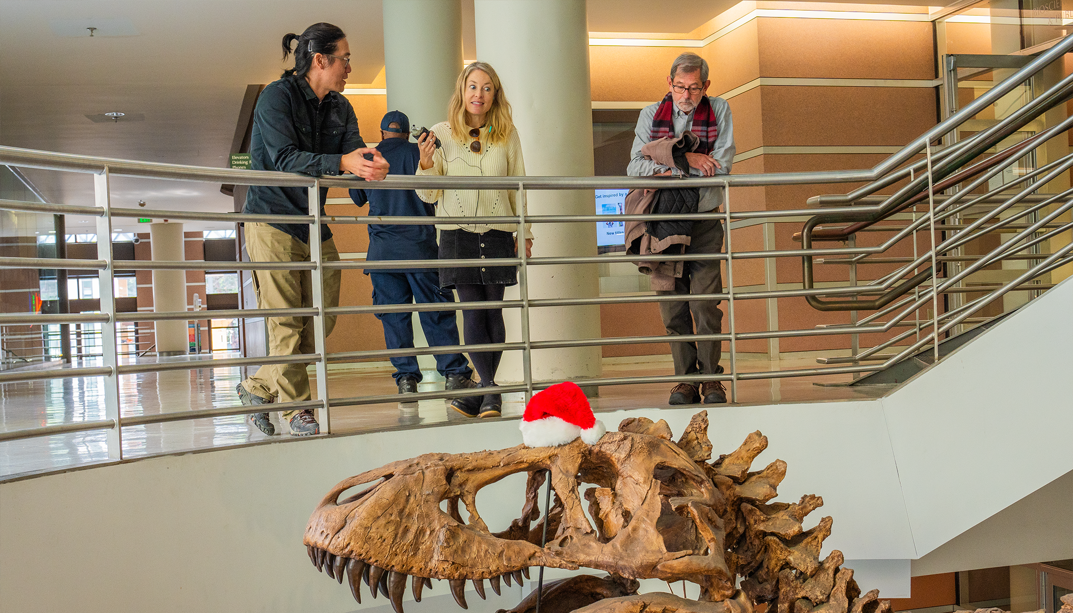 Jack Tseng talks to Anne Brice and Bob Sanders about a T. rex, which is on the floor below them