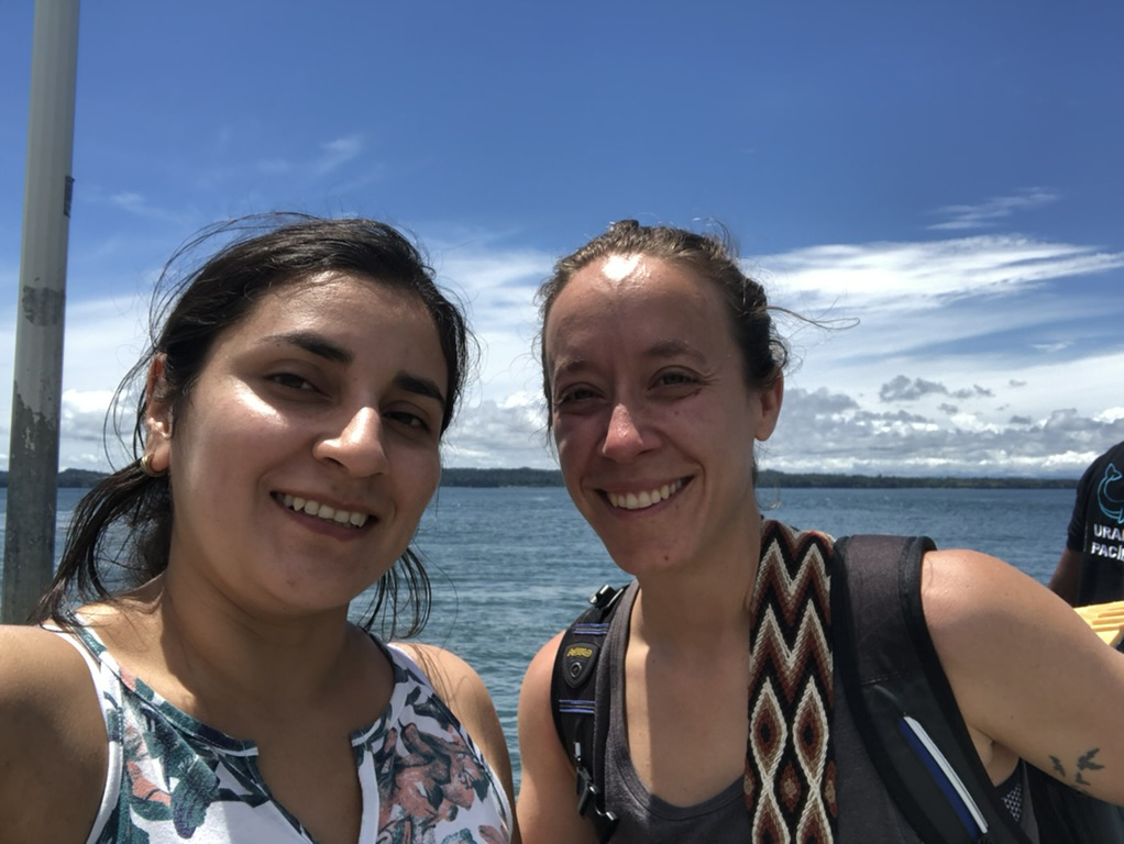 two smiling women on boat with blue sky and blue water behind them