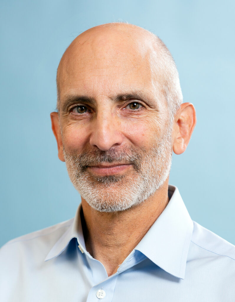 headshot of Ken Alex against a sky-blue background