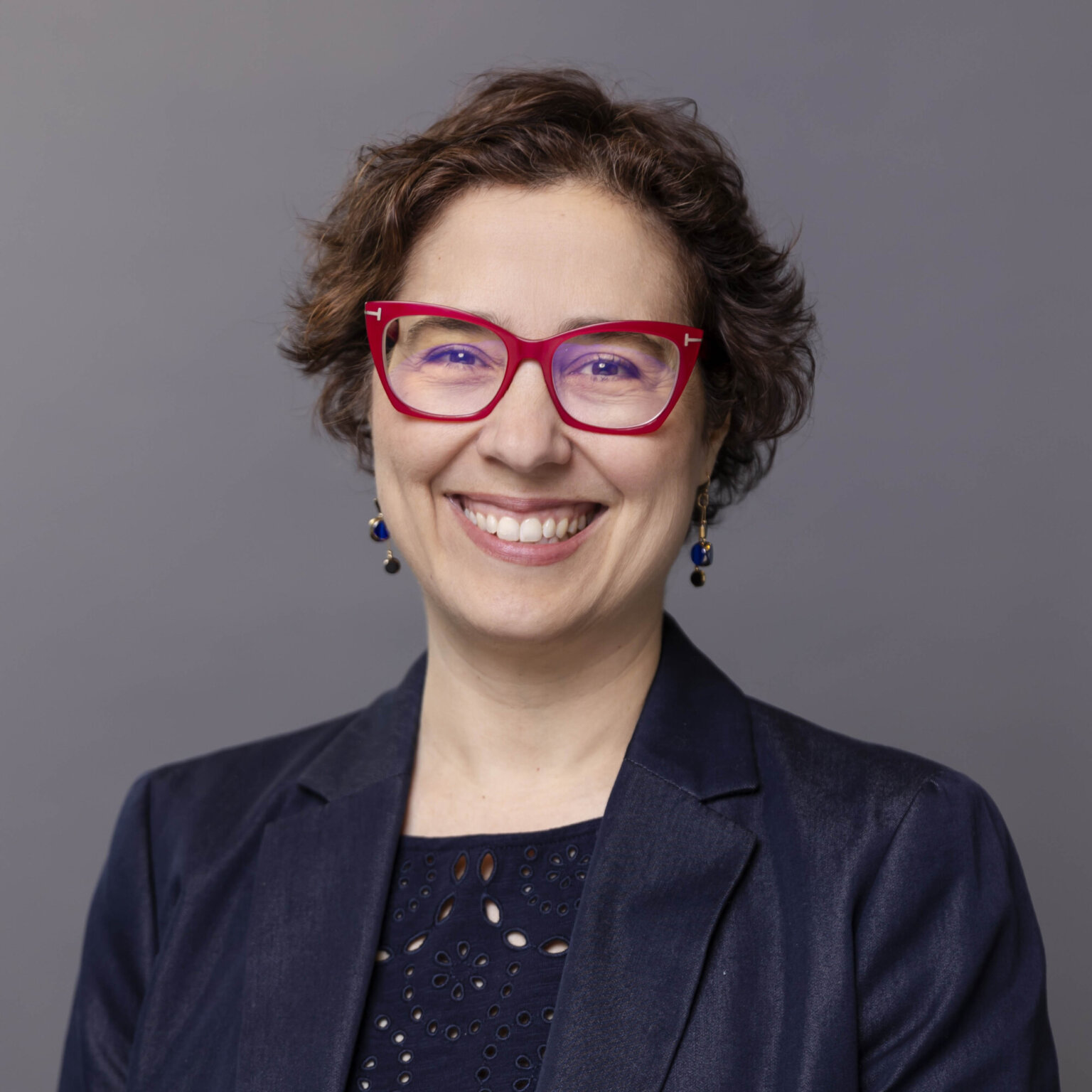 a headshot of a woman with short hair wearing red glasses