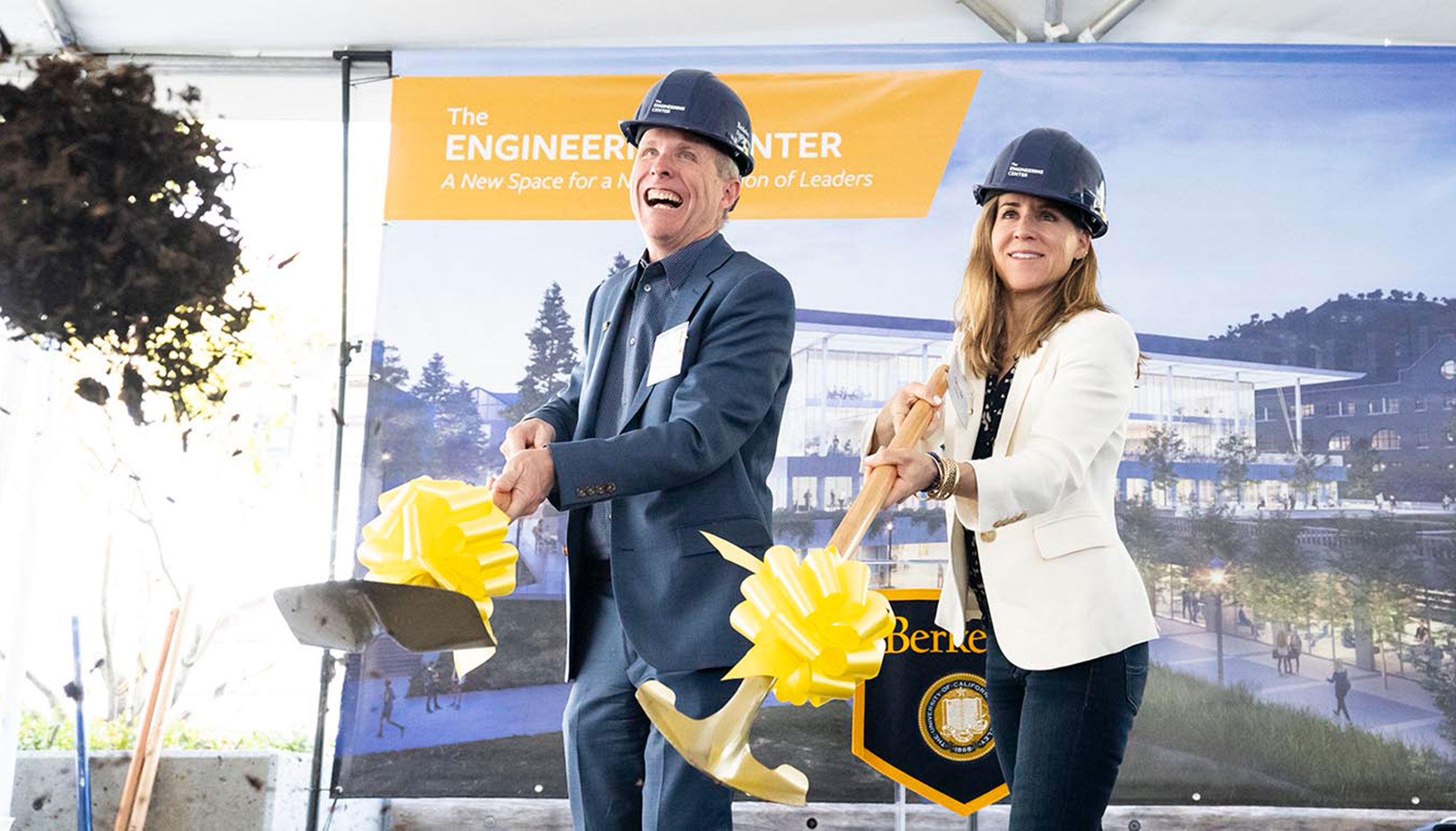 Two people wearing UC Berkeley scoop dirt with golden shovels.