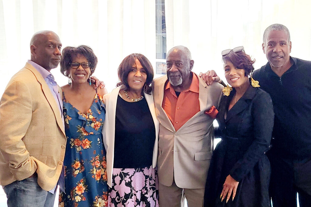 Family members of Professor Chris Schell stand with their arms around each other facing the camera. Their homes in LA County were burned in the Eaton Fire.