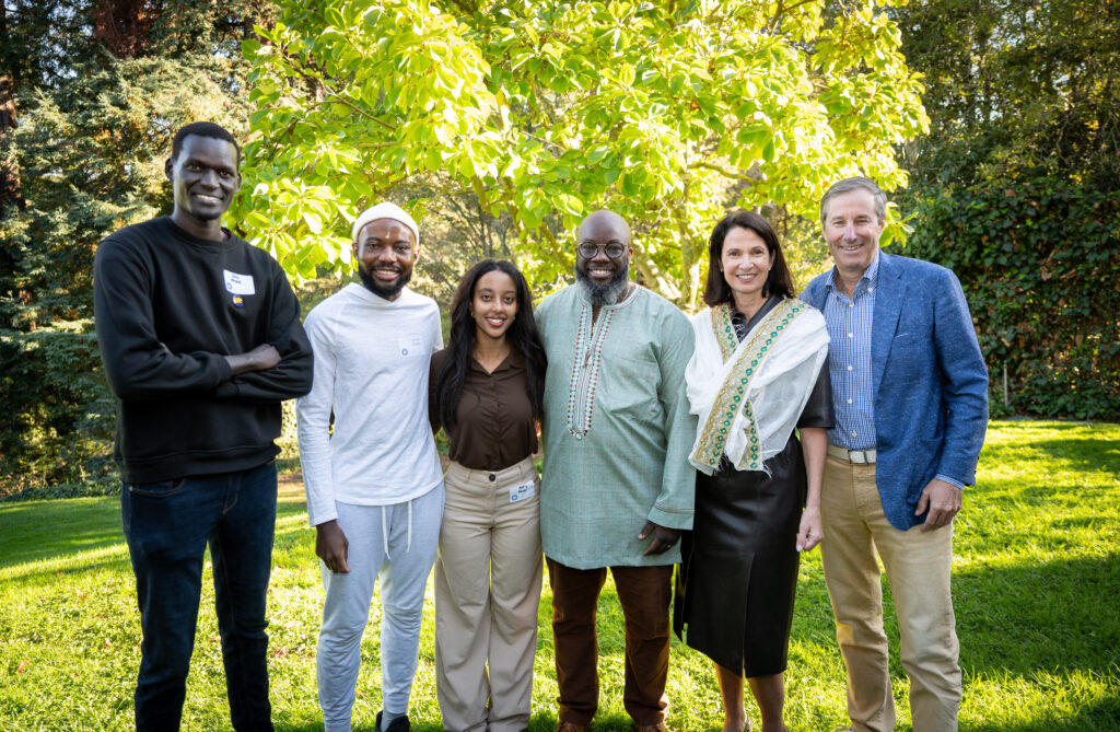 Six people, including three of the students who received the scholarship, stand for a group photo outdoors