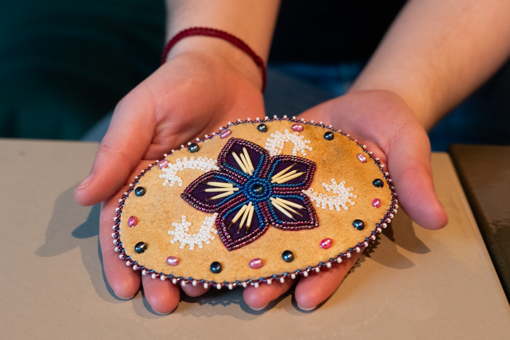 A student holds a large hair clip in her hands that was made for her of leather, beads and porcupine quills by an Indigenous artist in Alaska.