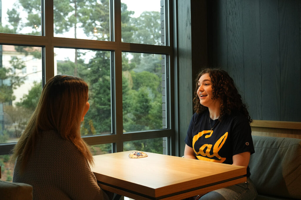 Roommates Erin Wall and Akira Son sit across a table from each other in Anchor House, where they share a double unit.