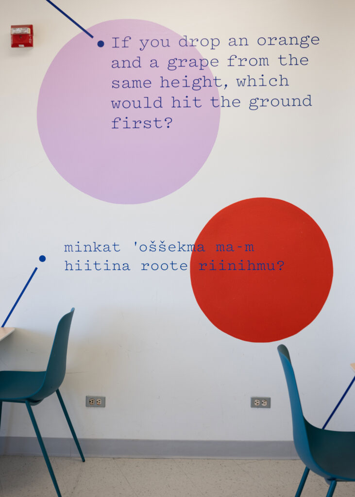 Questions in English and Chochenyo are printed on the wall of the lunchroom at the Lawrence Hall of Science, along with large painted circles in lavender and red.