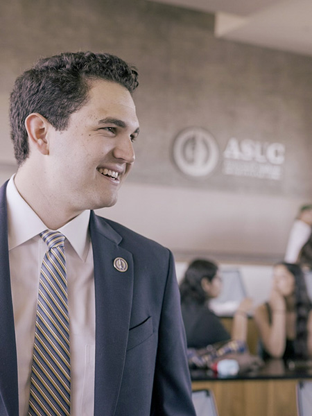 Max Rodman, an. ASUC senator, is wearing a suit, tie and a smile in the ASUC senate chambers.