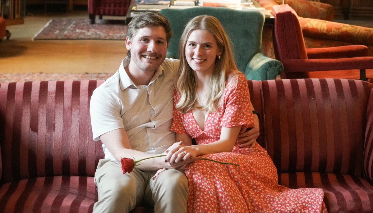 Trier Mortlock and Helen Kirkby sit close together on couch and smile happily