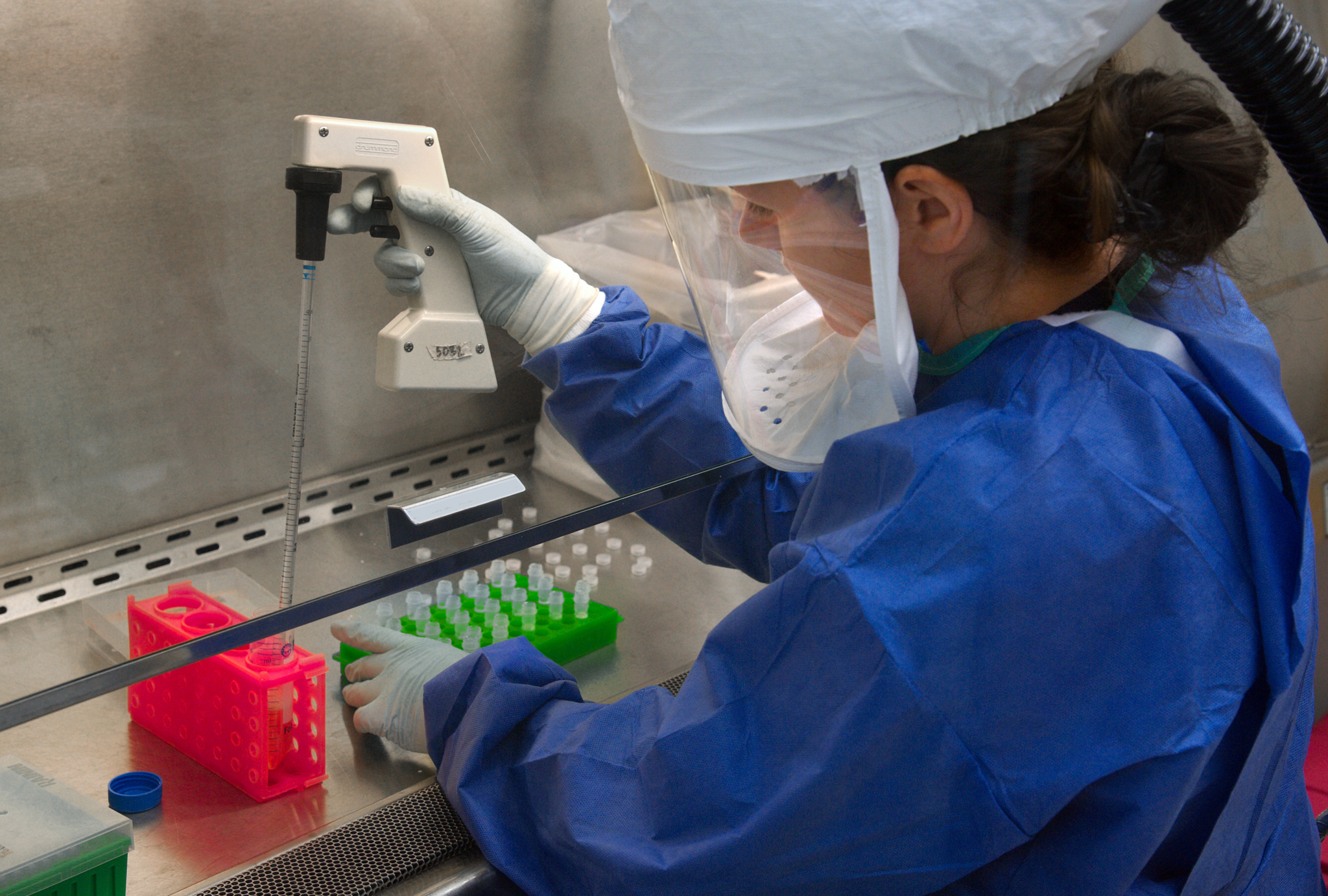 a woman in a lab suit uses a pipette in lab