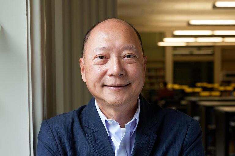 A bald man in a dress shirt smiles at the camera.